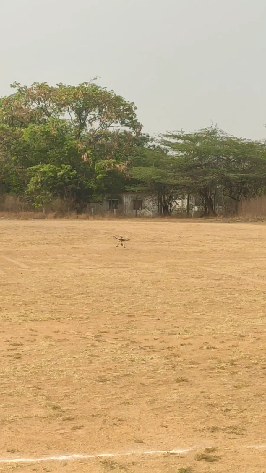 XD-D02 payload dropping drone in flight over an open field